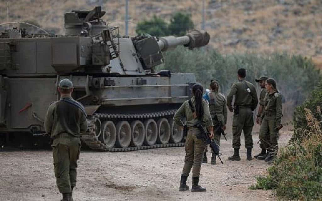 Israeli soldiers stand next to a self-propelled artillery gun near the Lebanese border to control Hezbollah