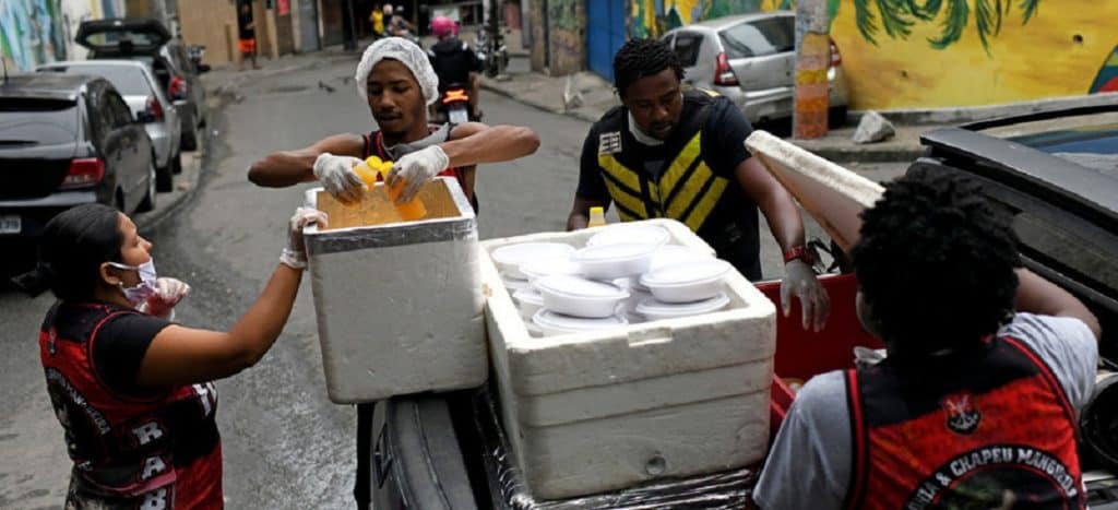 Un grupo de residentes del barrio marginal de Chapeu Mangueira, llevan cajas de comida para dar a las personas sin hogar en el barrio de Copacabana durante el brote de la enfermedad por coronavirus.