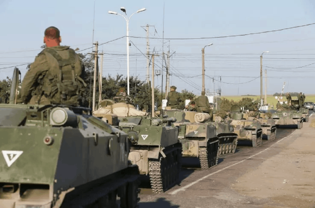 Russian military personnel sit atop armoured vehicles outside Kamensk-Shakhtinsky, Rostov Region,