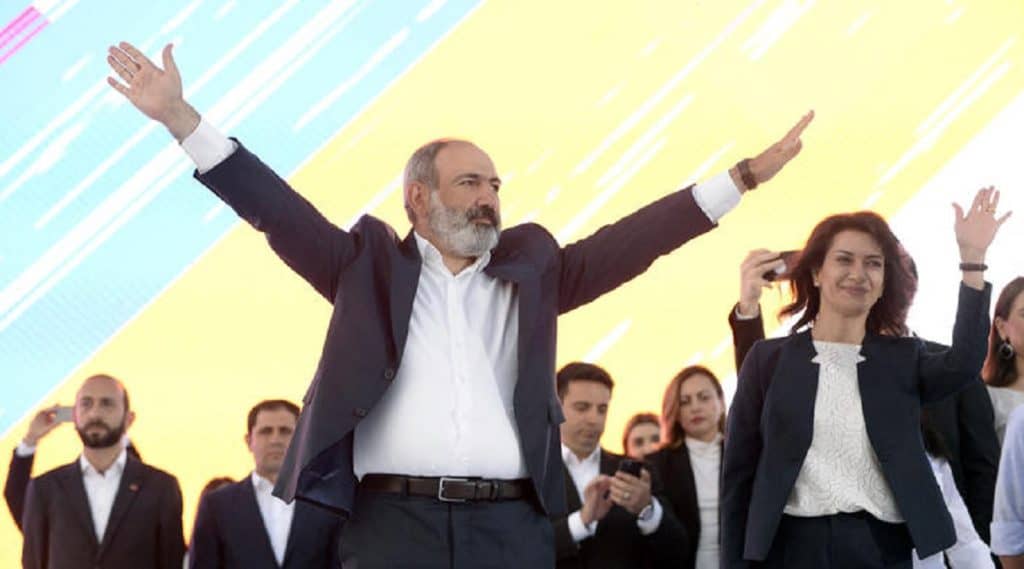 Премьер-министр Армении Никол Пашинян машет руками на сцене во время предвыборного митинга