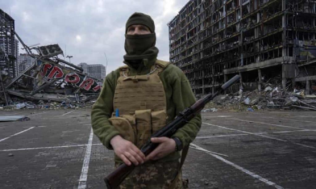 Ukrainian soldier in front a shopping centre in Kyiv destroyed by Russian bombing.